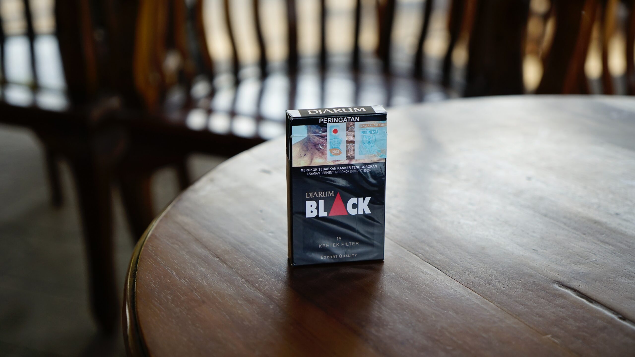 Black cigarette box on top of brown wooden table